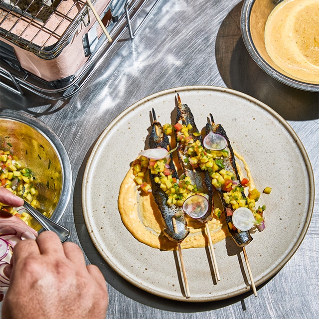Arenque a la brasa en brocheta con pico de gallo de mango & rouille